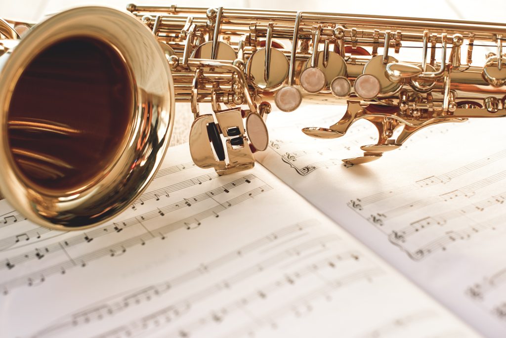 Closeup of a beautiful and shiny golden saxophone lying on music notes