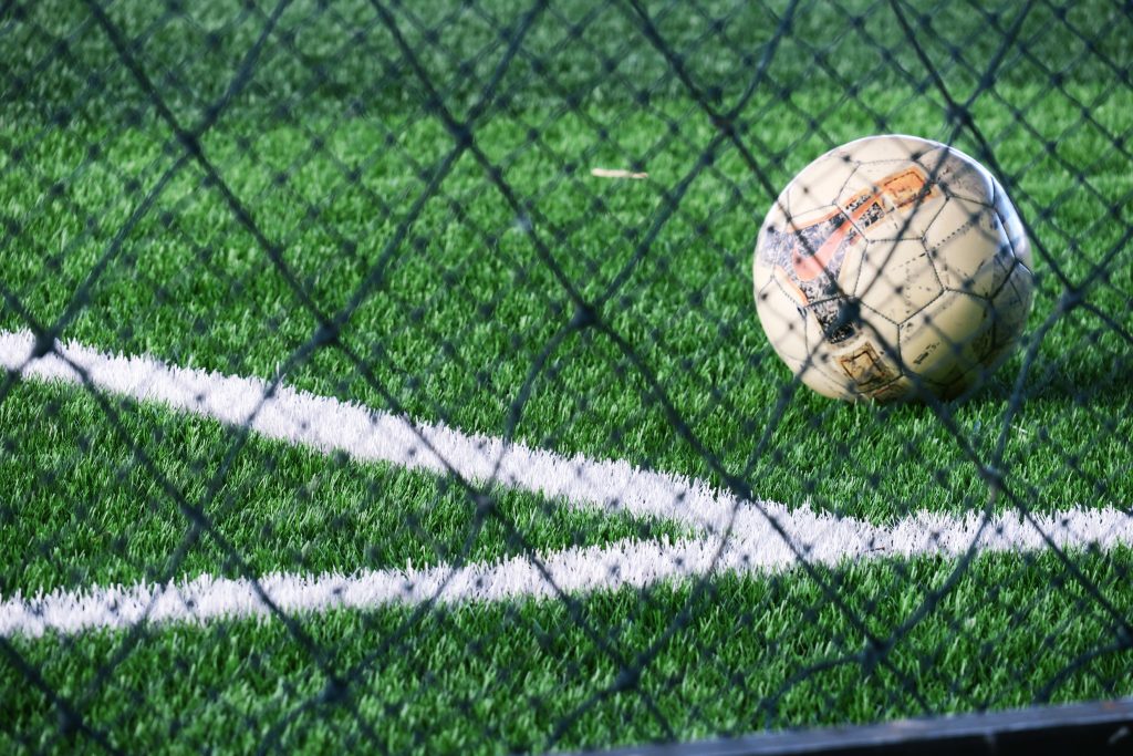 Soccer ball placed near court line in green soccer field stadium