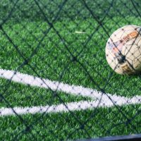 Soccer ball placed near court line in green soccer field stadium